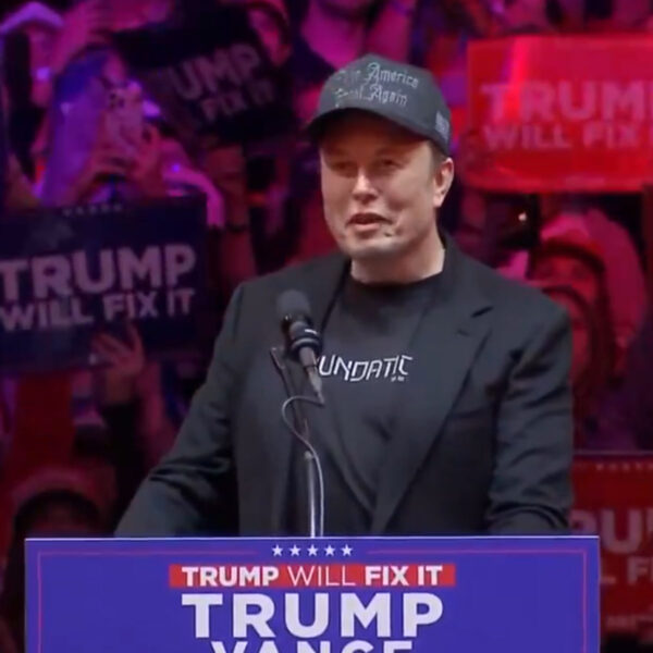 Elon Musk is on the stage wearing his Dark Gothic MAGA hat.7